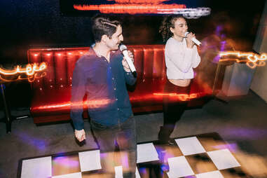 A group of friends enjoys an evening on the town at a dance hall karaoke bar. 
