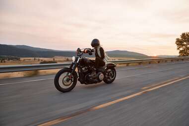 woman driving motorcycle past open fields