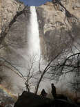 People stand below as water flows forcefully down Bridalveil Fall in Yosemite Valley