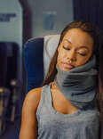 woman sleeping on a plane wearing trtl travel pillow 