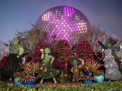 Topiaries of the Encanto movie characters in front of the Epcot ball at Disney World.