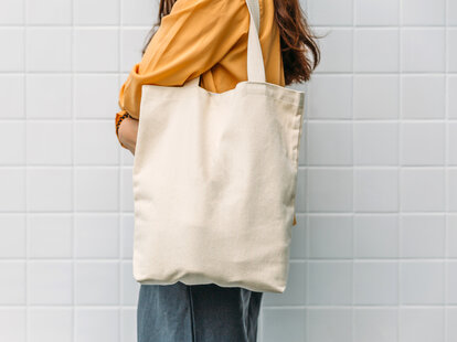 A woman is holding a canvas tote bag