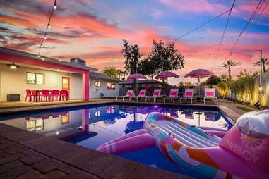 A house with a pink pool float and pink lawn furniture. 