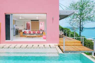 The exterior of a pink villa in Costa Rica with an infinity pool sitting on a cliff overlooking the Pacific ocean. 