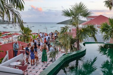 A roof top bar in St. Thomas that has a pool and view of the ocean.