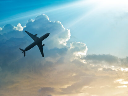 An airplane in a cloudy blue sky.