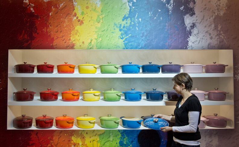 A person looking at the various Le Creuset colored sauce pans at a store in Germany.