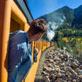 man looking out at scenic view from train window