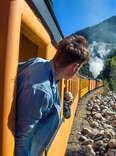 man looking out at scenic view from train window