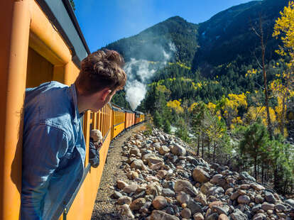 man looking out at scenic view from train window