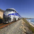 Amtrak passenger train on tracks running alongside Pacific Ocean beaches near Santa Barbara on the west coast of California