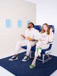 A couple sitting in airplane seats wearing matching sweatsuits. 
