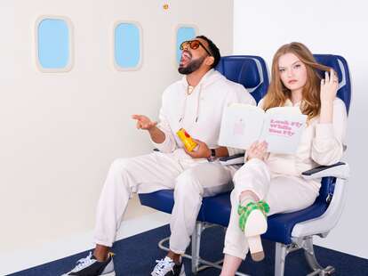 A couple sitting in airplane seats wearing matching sweatsuits. 