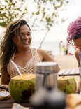 People enjoying their vacation with tropical drinks outdoors at a beach bar