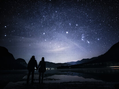Couple holding hands by the lake and gazing at the star