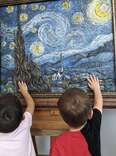 Two children touch art at Envision Arts Gallery