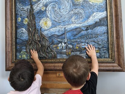 Two children touch art at Envision Arts Gallery