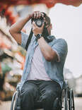 Man in wheelchair using camera