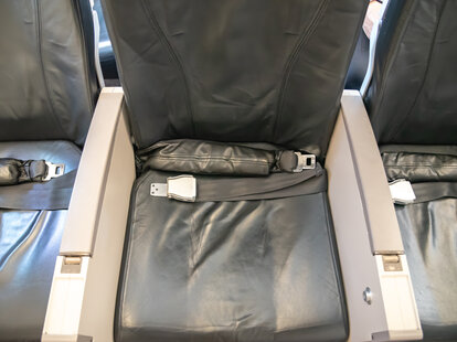 The middle seat with its armrests on an economy flight airplane