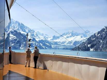 tourists admiring snowy peaks from deck of cruise ship