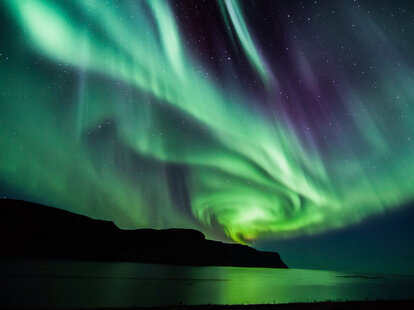 Spiraling northern lights over a lake.