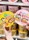 hand holding out containers of instant noodles at familymart malaysia