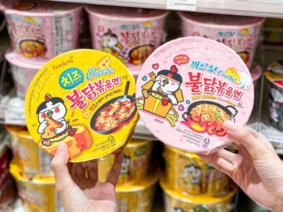 hand holding out containers of instant noodles at familymart malaysia