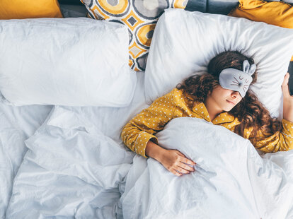 woman laying in bed with eye mask and iphone
