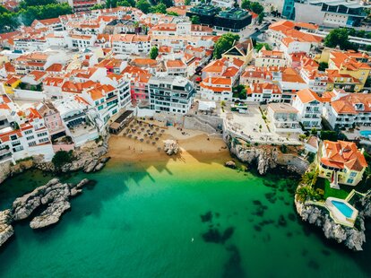 Drone aerial view of Praia da Rainha and the city of Cascais, Portugal on a sunny day.