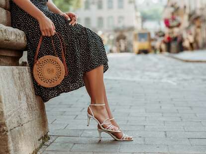 woman wearing heels and trendy straw bag