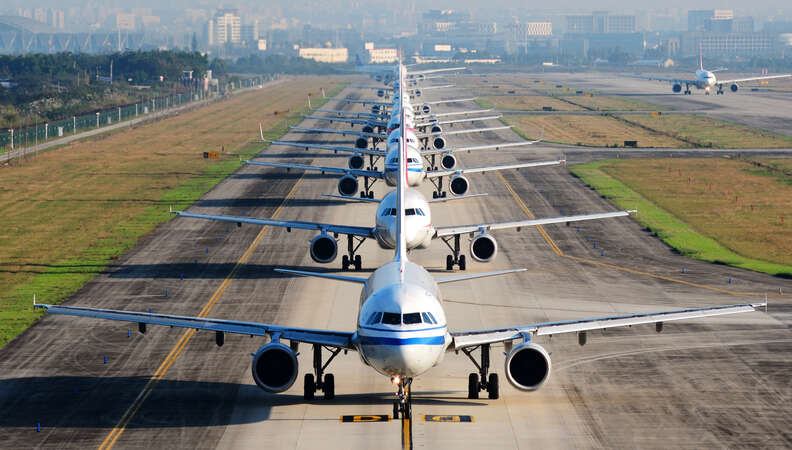 long line of airplanes on runway