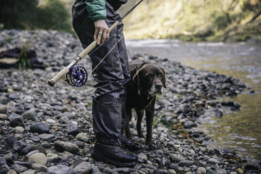 woman holding fishing pole beside dog