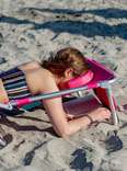 woman reading while lying down on ostrich beach chair 