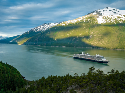 An aerial view of a Holland America Line cruise ship sailing in Alaska during the day.