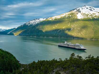 An aerial view of a Holland America Line cruise ship sailing in Alaska during the day. 