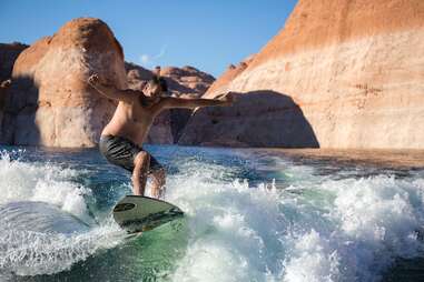 man riding surfboard in lake powell