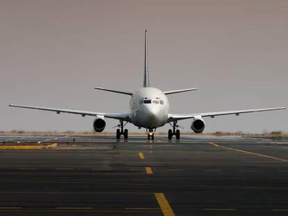 A white airplane entering a platform on a very hot day.