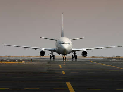 A white airplane entering a platform on a very hot day.