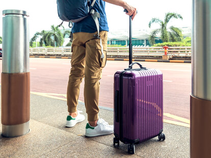 Passenger waiting for a taxi at the airport with suitcase