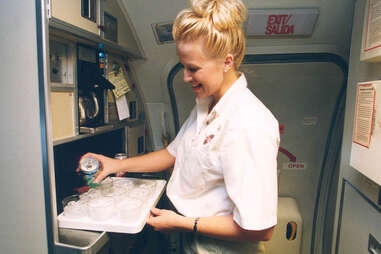 Flight attendant pouring drinks on a plane