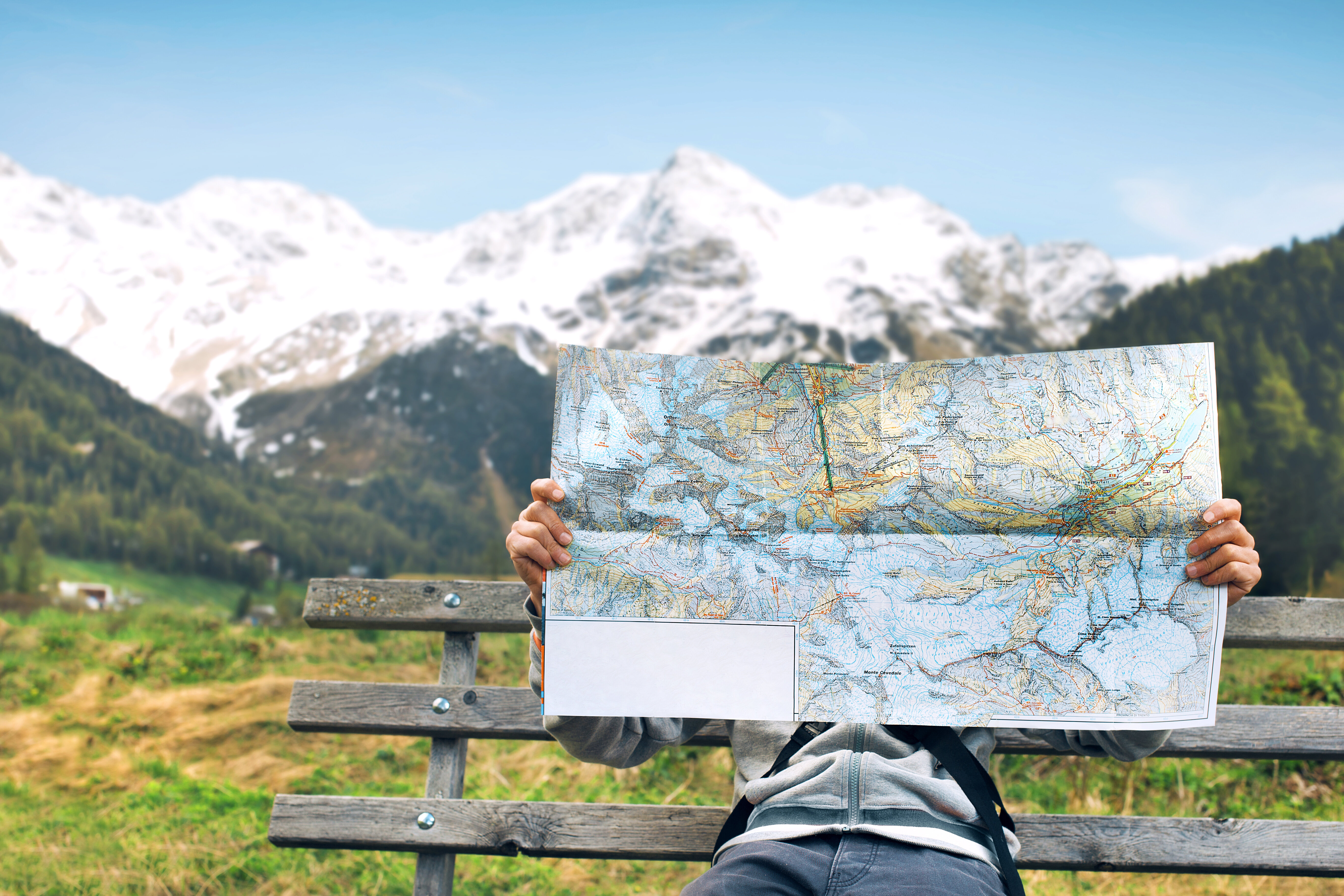 person reading a paper map with mountains in the background