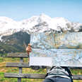 person reading a paper map with mountains in the background