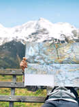 person reading a paper map with mountains in the background