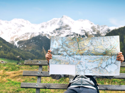 person reading a paper map with mountains in the background