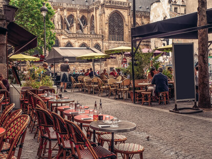 Cozy street with tables of cafe in Paris, France. Architecture and landmarks of Paris.