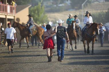 a man and a woman from behind, walking at the rodeo