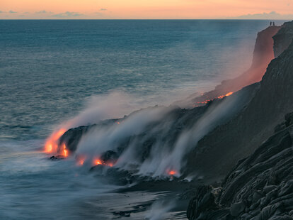Lava from the Kilauea volcano, flows into the Pacific ocean near Kalapana, while people watch the spectacle from up above at Volcanoes National Park on the Big Island of Hawaii.
