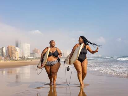 Two women carrying surfboards 