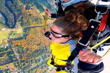 close up of woman sky diving over fall foliage