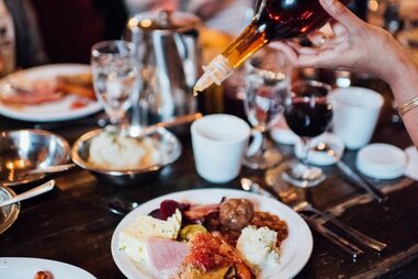 person pouring syrup over breakfast